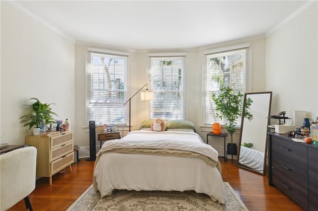 bedroom with multiple windows, crown molding, and wood finished floors