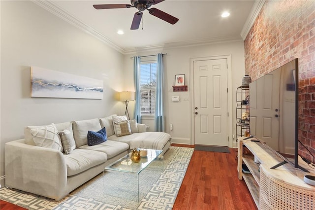 living area featuring brick wall, dark wood-type flooring, baseboards, and ornamental molding