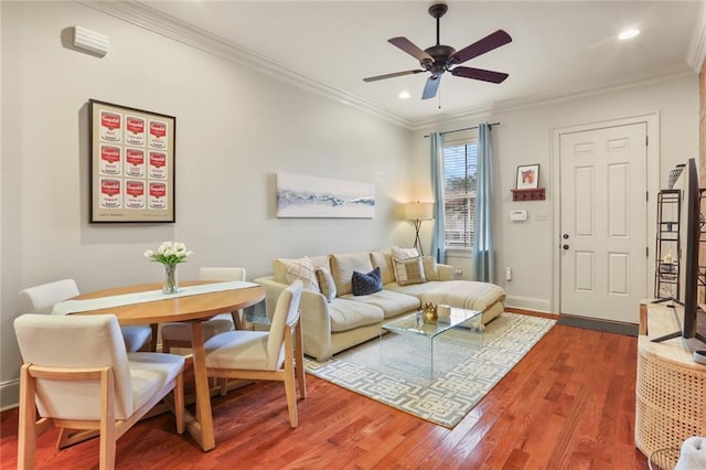 living room featuring baseboards, a ceiling fan, wood finished floors, and crown molding