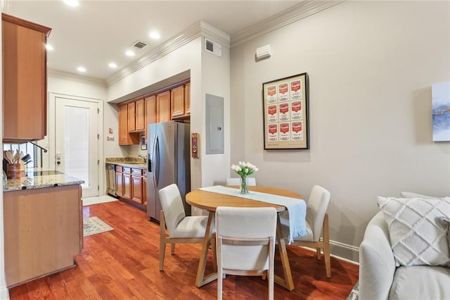 dining area featuring baseboards, visible vents, light wood-style flooring, electric panel, and ornamental molding