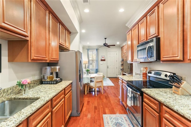 kitchen with light wood-style flooring, a ceiling fan, a sink, appliances with stainless steel finishes, and crown molding