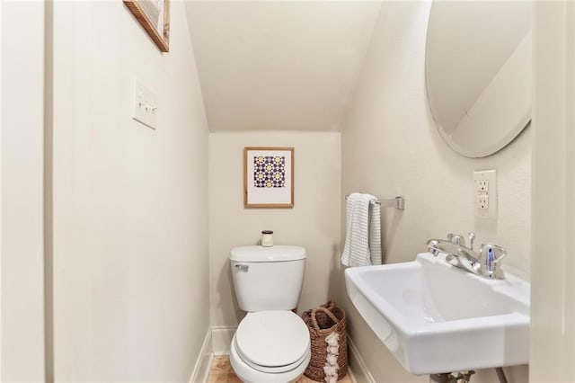 half bathroom featuring a sink, baseboards, and toilet