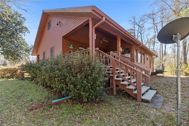 view of side of property featuring a deck, ceiling fan, and stairs