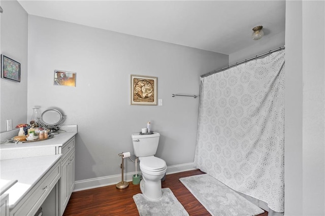 full bath with curtained shower, baseboards, toilet, wood finished floors, and vanity