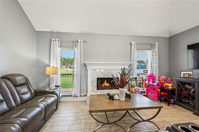 living area featuring wood finished floors, a high end fireplace, and vaulted ceiling