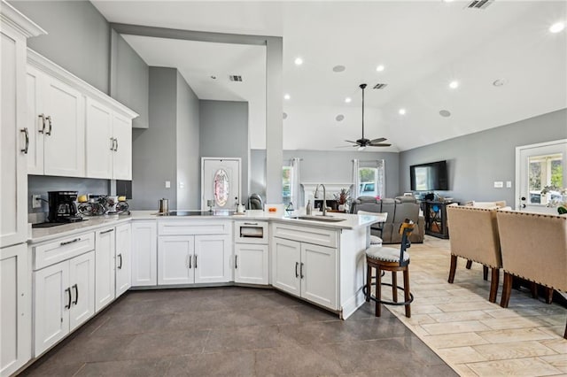 kitchen featuring a peninsula, plenty of natural light, light countertops, and a sink