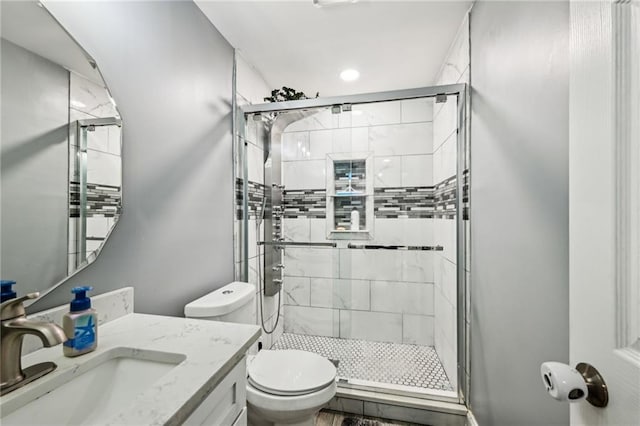 bathroom featuring toilet, a stall shower, and vanity