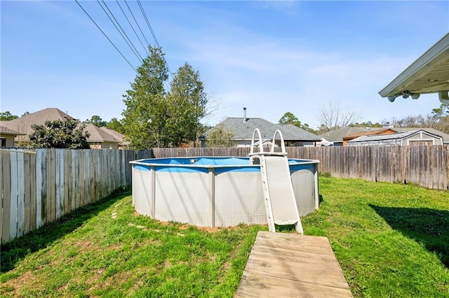 view of swimming pool with a yard, a fenced in pool, and a fenced backyard