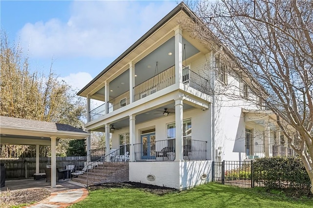 view of front of property with a patio, a balcony, a ceiling fan, fence, and stucco siding