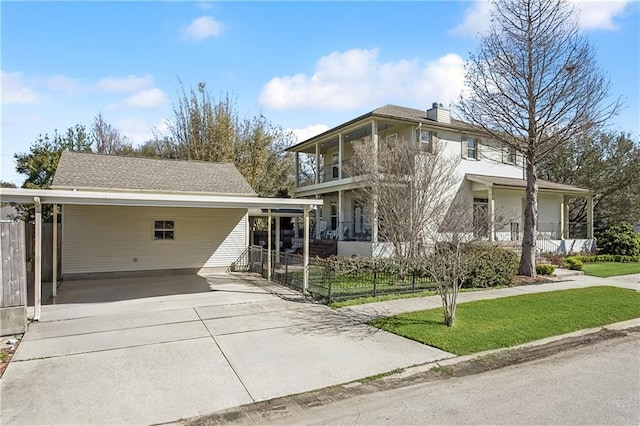 view of front of house featuring driveway, a balcony, fence, a carport, and a chimney