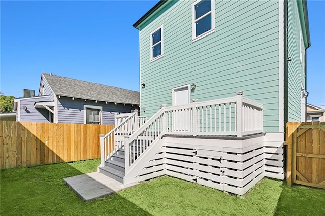 rear view of house featuring a fenced backyard, stairway, a wooden deck, and a yard