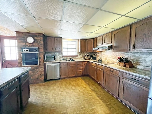 kitchen featuring under cabinet range hood, stainless steel dishwasher, wall oven, light countertops, and black electric cooktop