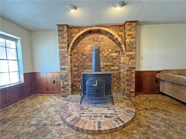 interior details featuring a textured ceiling, wooden walls, carpet, and wainscoting