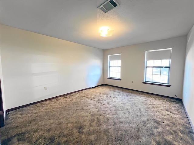 carpeted spare room featuring baseboards and visible vents