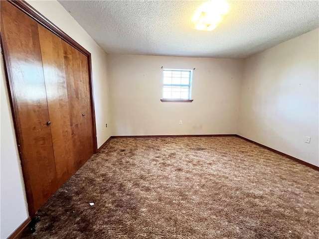 unfurnished bedroom featuring a closet, carpet flooring, a textured ceiling, and baseboards