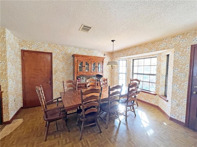 dining room with visible vents, baseboards, a textured ceiling, and wallpapered walls