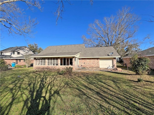 rear view of house featuring a yard, brick siding, a garage, and a sunroom