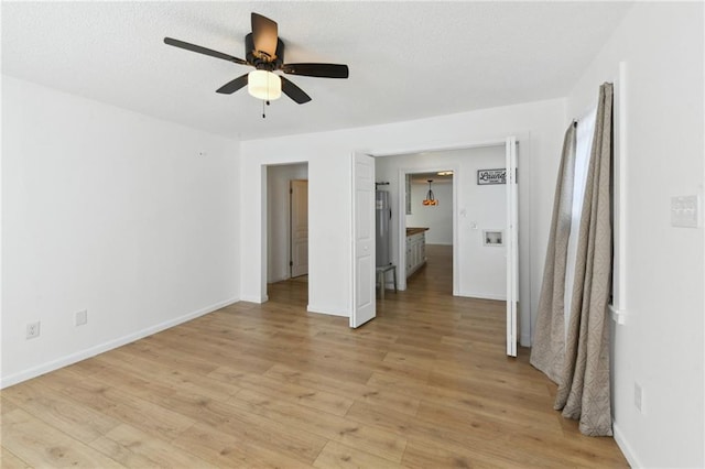 unfurnished bedroom featuring ceiling fan, baseboards, light wood-type flooring, and a textured ceiling