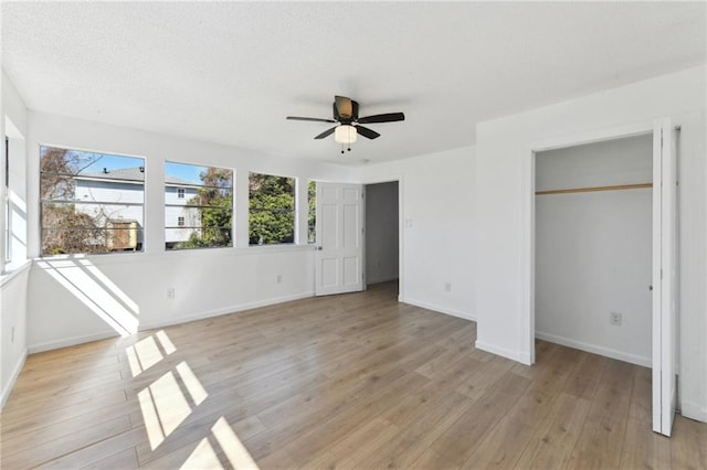 unfurnished bedroom featuring ceiling fan, a textured ceiling, light wood-type flooring, and baseboards