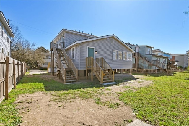 rear view of property featuring stairway, a yard, and fence