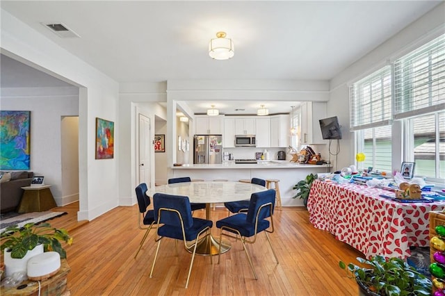 dining space featuring visible vents, light wood-style flooring, and baseboards