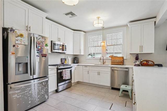 kitchen featuring a sink, appliances with stainless steel finishes, white cabinets, and light countertops