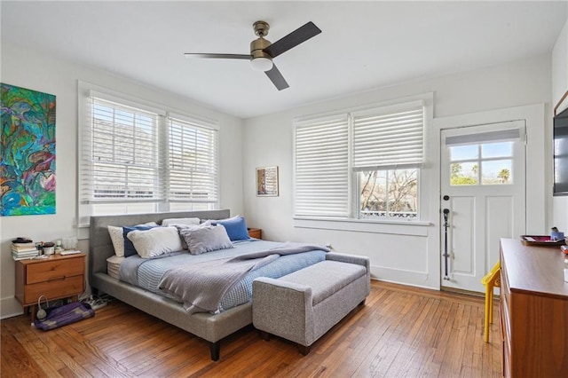 bedroom featuring multiple windows, baseboards, light wood-style flooring, and ceiling fan