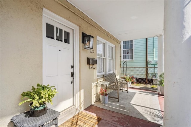 doorway to property featuring stucco siding and a porch