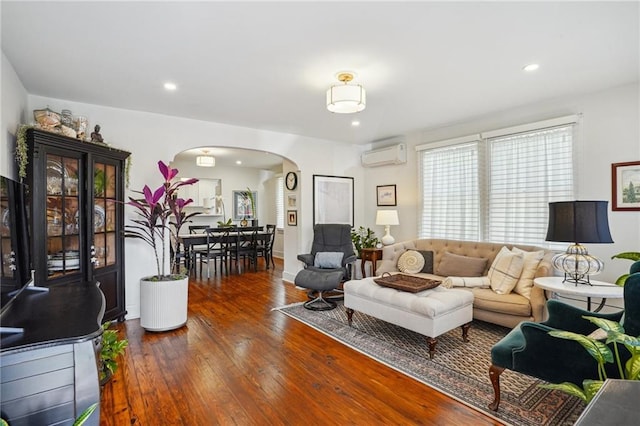 living area with recessed lighting, arched walkways, wood-type flooring, and a wall unit AC