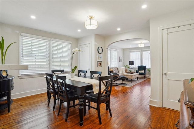 dining space with recessed lighting, baseboards, arched walkways, and wood-type flooring