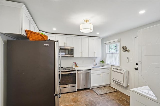 kitchen with heating unit, appliances with stainless steel finishes, white cabinetry, and a sink