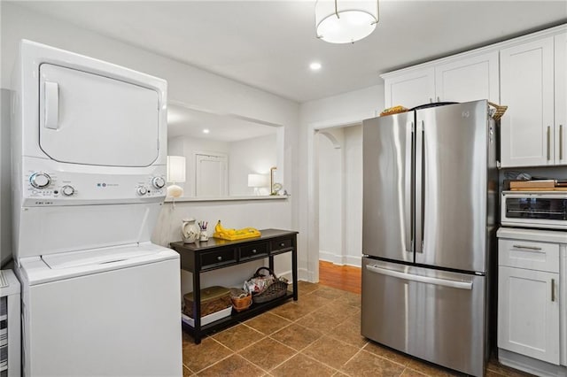 washroom with dark tile patterned floors, a toaster, laundry area, recessed lighting, and stacked washer / drying machine