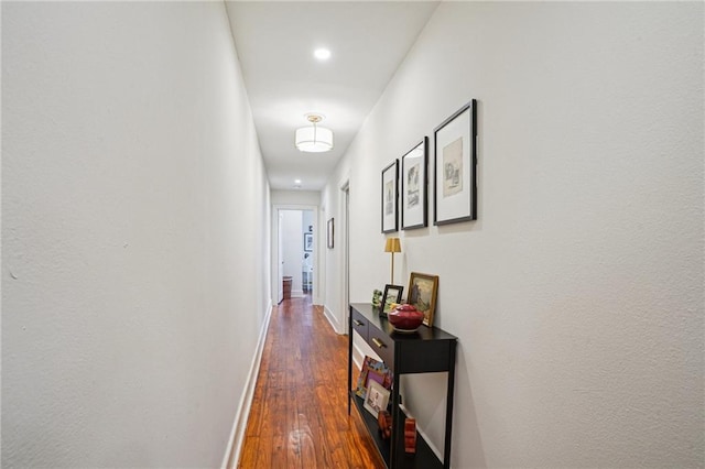 corridor with baseboards and dark wood-style floors