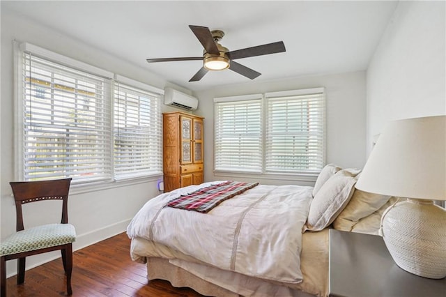 bedroom with ceiling fan, a wall mounted AC, baseboards, and wood finished floors