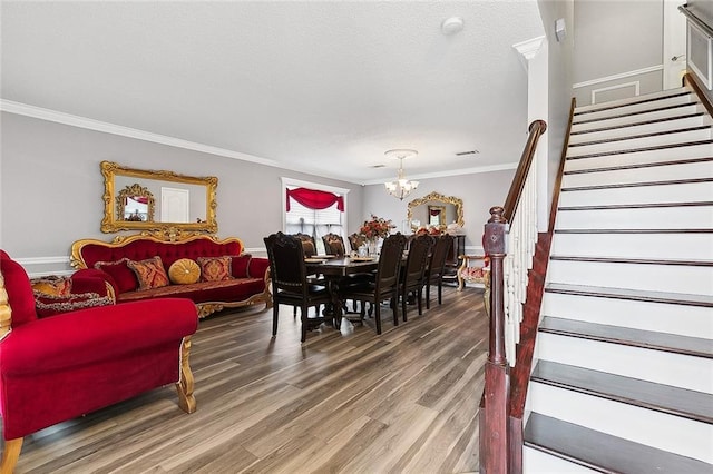 dining room with ornamental molding, stairs, an inviting chandelier, and wood finished floors