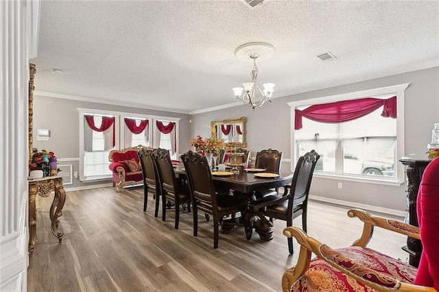 dining area featuring a notable chandelier, wood finished floors, visible vents, and ornamental molding