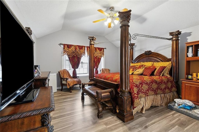 bedroom featuring light wood-type flooring, a textured ceiling, and vaulted ceiling