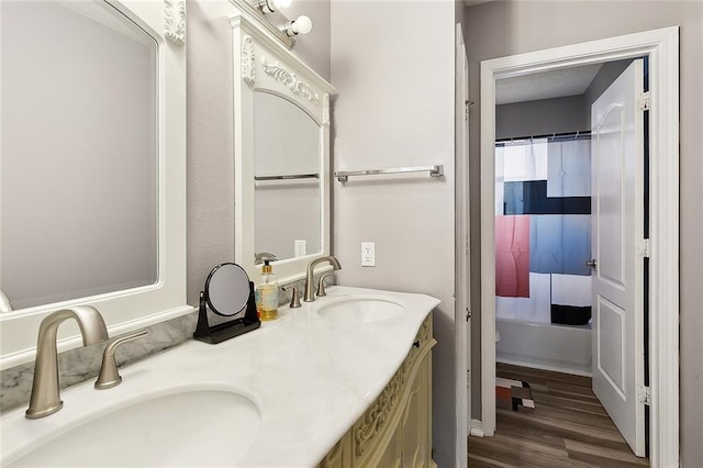 full bath with a sink, shower / bath combo, wood finished floors, and double vanity