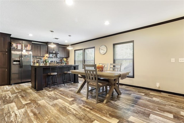 dining space featuring wood finished floors, recessed lighting, and ornamental molding