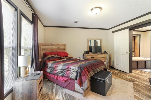 bedroom featuring wood finished floors, visible vents, and crown molding