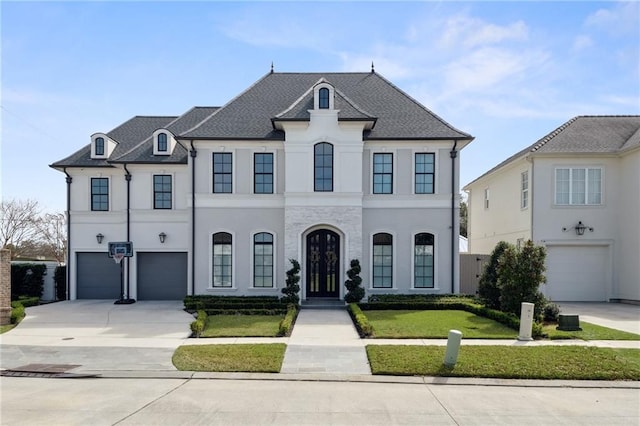 french country home with stucco siding, driveway, an attached garage, and a shingled roof