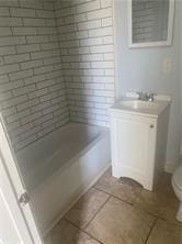 full bath featuring shower / bath combination, toilet, vanity, and tile patterned flooring