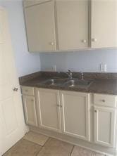 bar featuring light tile patterned floors and a sink