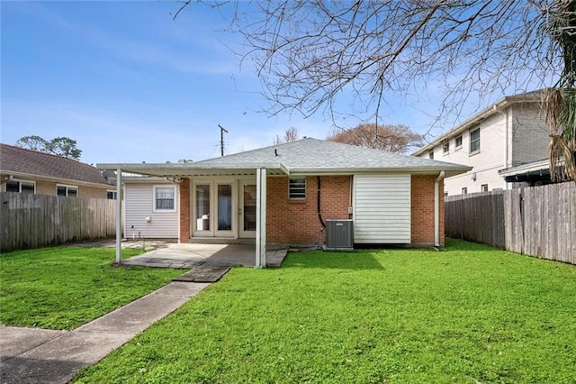 rear view of property featuring a lawn, a fenced backyard, brick siding, and a patio area