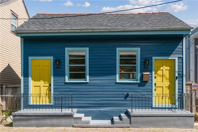 view of front of house with roof with shingles and fence