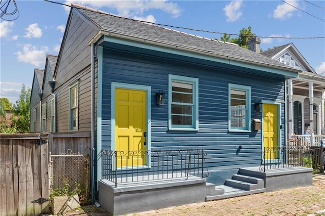 view of front of house featuring roof with shingles and fence