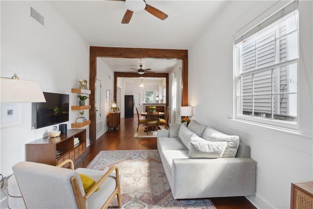 living room featuring visible vents, baseboards, a ceiling fan, and wood finished floors