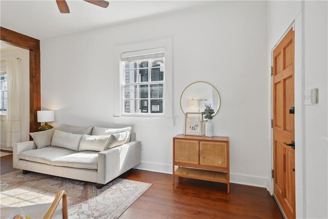 living area featuring ceiling fan, baseboards, and wood finished floors