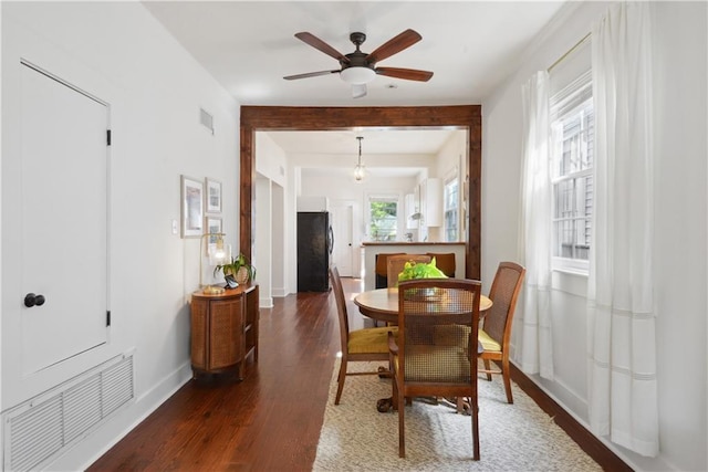 dining space with a ceiling fan, wood finished floors, visible vents, and baseboards