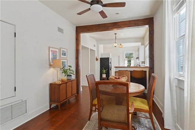 dining space featuring dark wood finished floors, ceiling fan with notable chandelier, baseboards, and visible vents